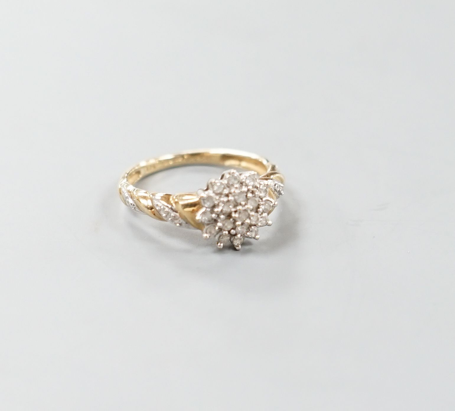 A modern 9ct gold and diamond cluster ring, with diamond chip set shoulders, size P, gross weight 2.5 grams.